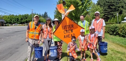 Adopt a Street participants smile in front of sign. 