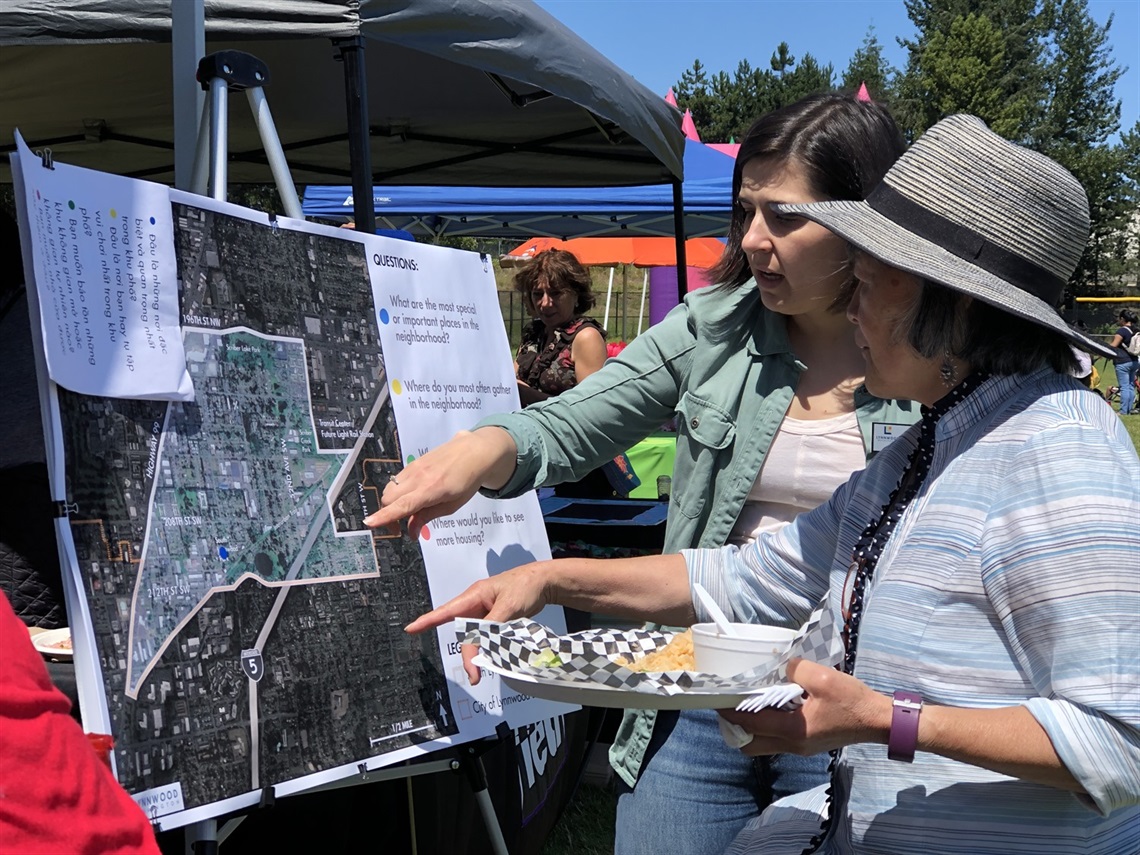 City Planning Staff talking to community member at Fair on 44th