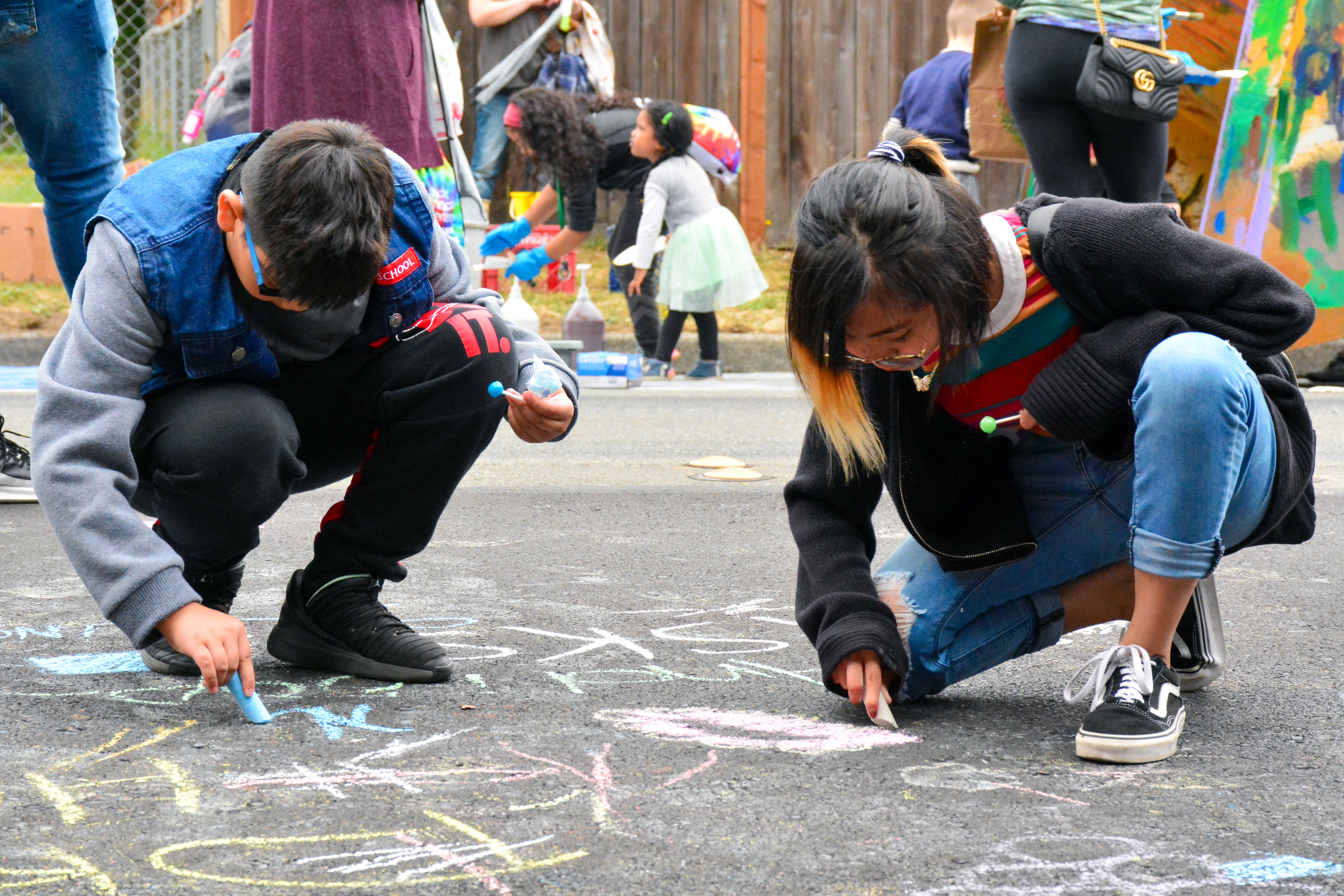 Kids create art with chalk on asphalt